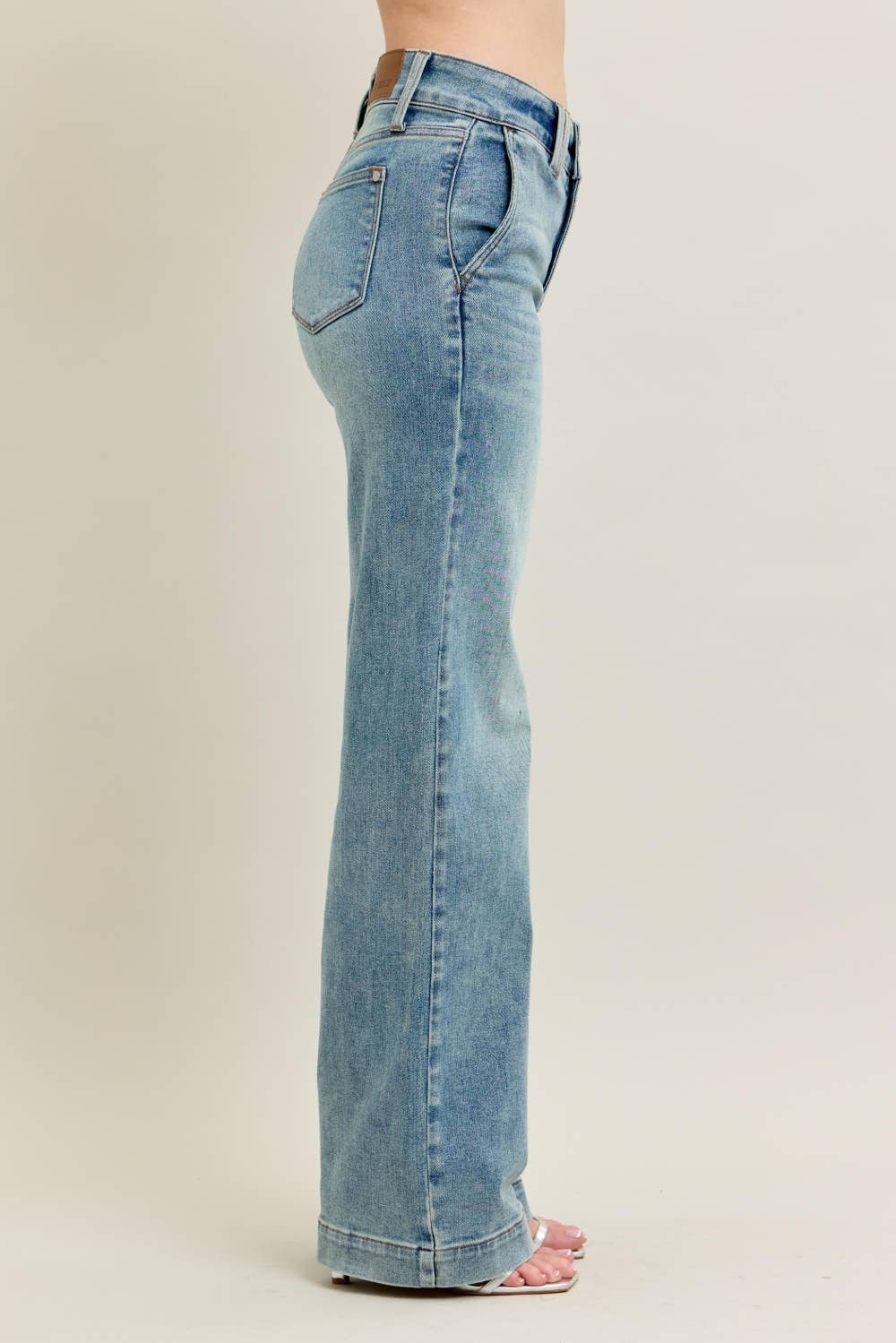 Light blue jeans worn by a person on a beige background