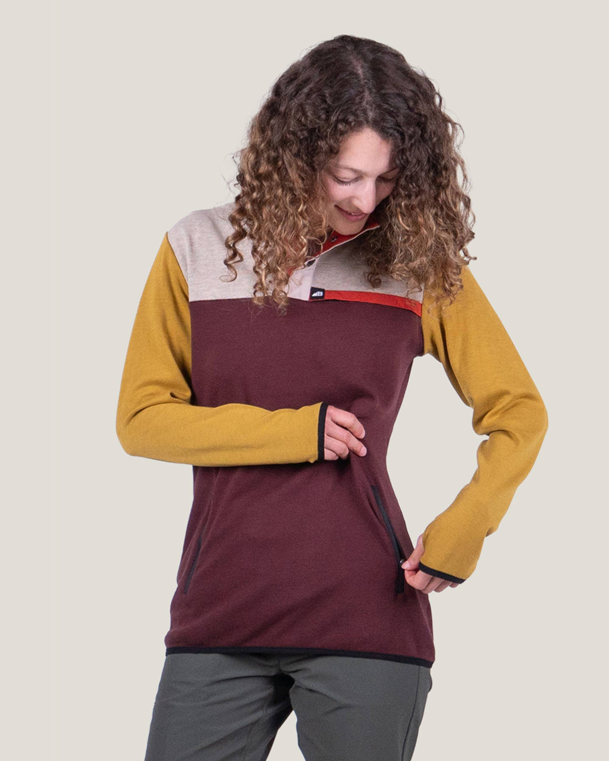 Person wearing a multicolored pullover with a neutral background