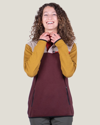 Person wearing a maroon apron over a mustard yellow long-sleeve shirt on a beige background