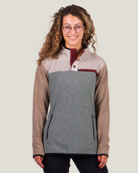 Woman wearing a gray and brown pullover with a plain background