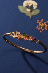 Decorative gold bracelet with gemstones on a blue background