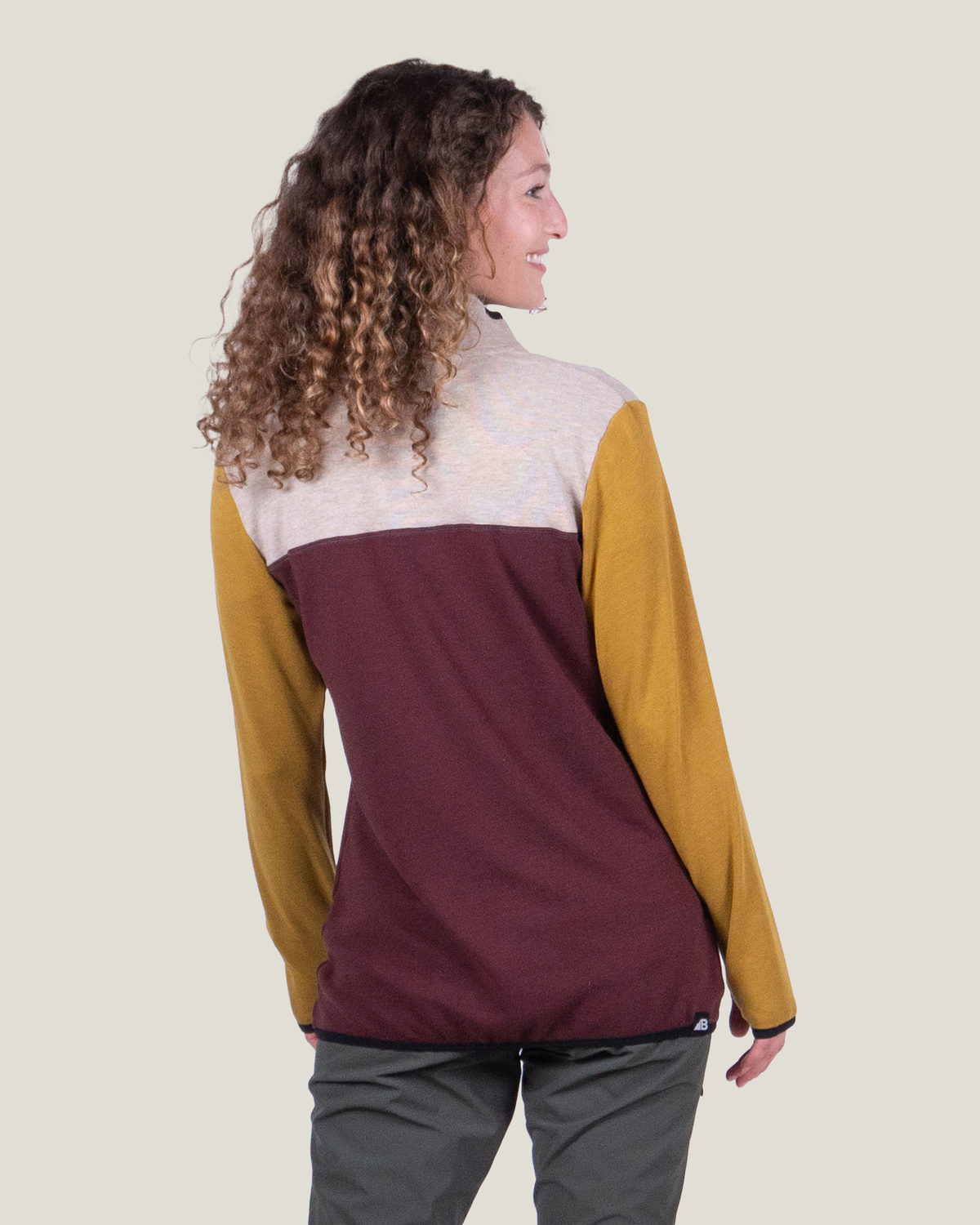 Person wearing a three-color jacket with a neutral background