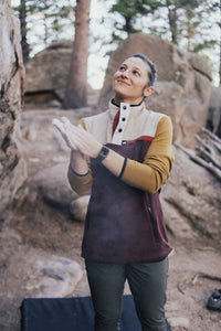 Person in a maroon and yellow jacket standing in a rocky outdoor setting