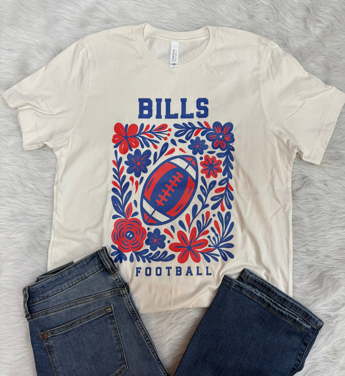 Woman wearing a colorful blouse and blue jeans standing outdoors.