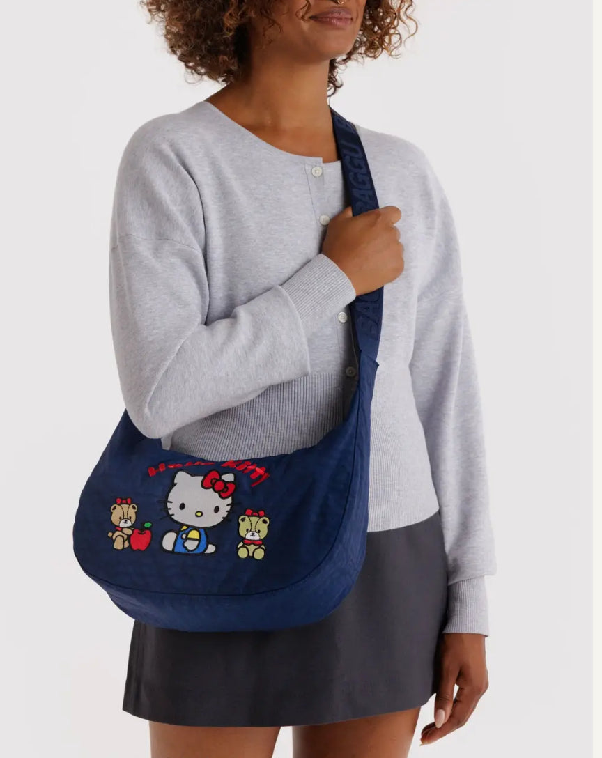 Person holding a blue bag with Hello Kitty design against a white background