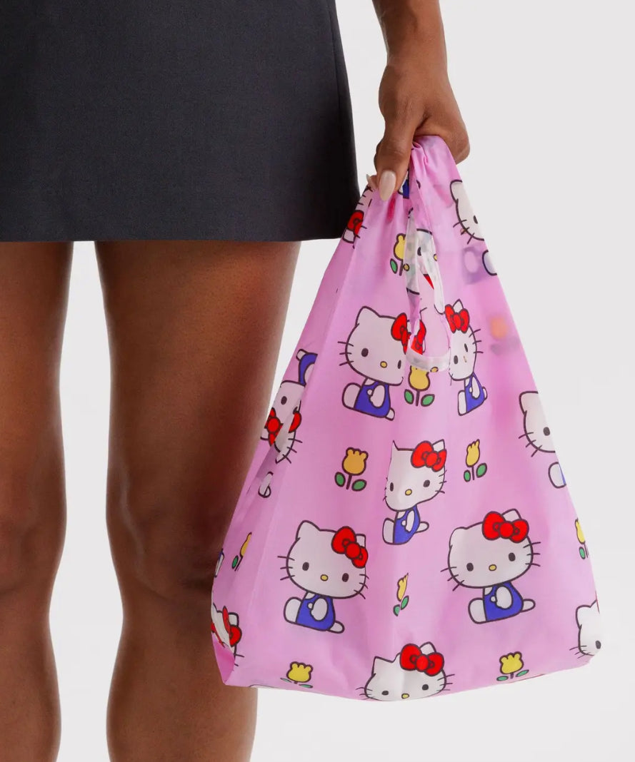 Person holding a pink Hello Kitty patterned bag against a neutral background