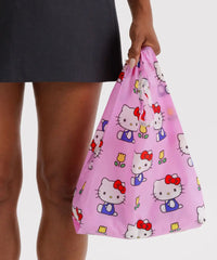 Person holding a pink Hello Kitty patterned bag against a neutral background