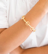 Gold bracelet on a person's wrist with a white background