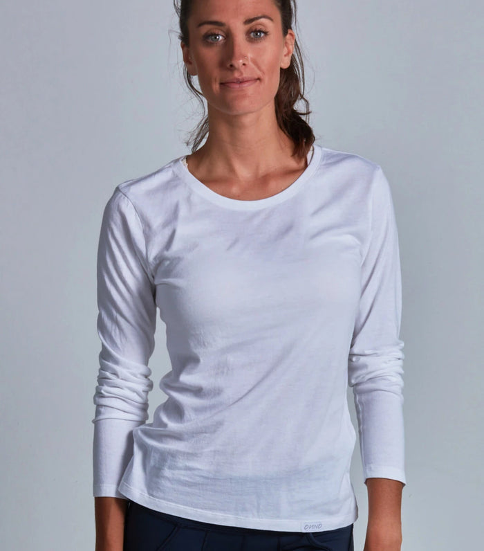 Woman wearing a white long-sleeve shirt against a gray background