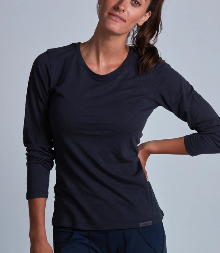 Woman wearing a black long-sleeve top against a gray background