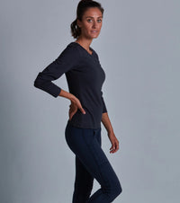 Woman wearing a dark blue long-sleeve top and pants against a gray background
