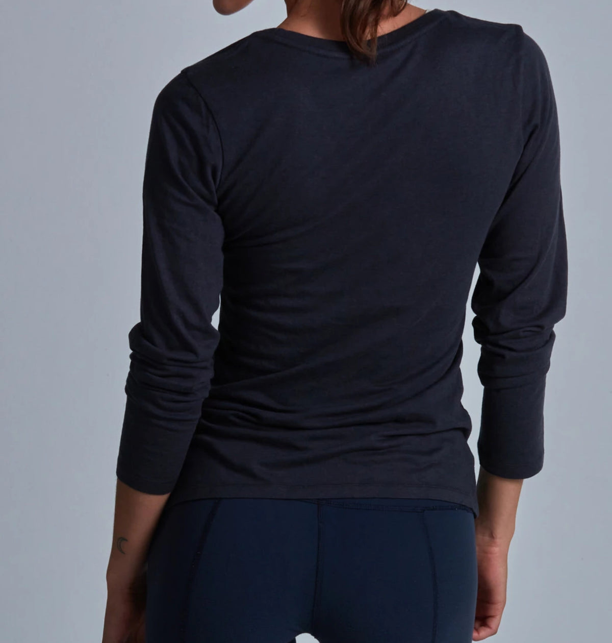 Person wearing a black long-sleeve shirt against a gray background