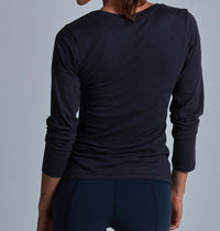 Person wearing a black long-sleeve shirt against a gray background