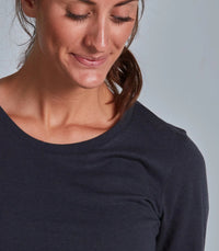 Woman wearing a dark blue long-sleeve shirt against a gray background