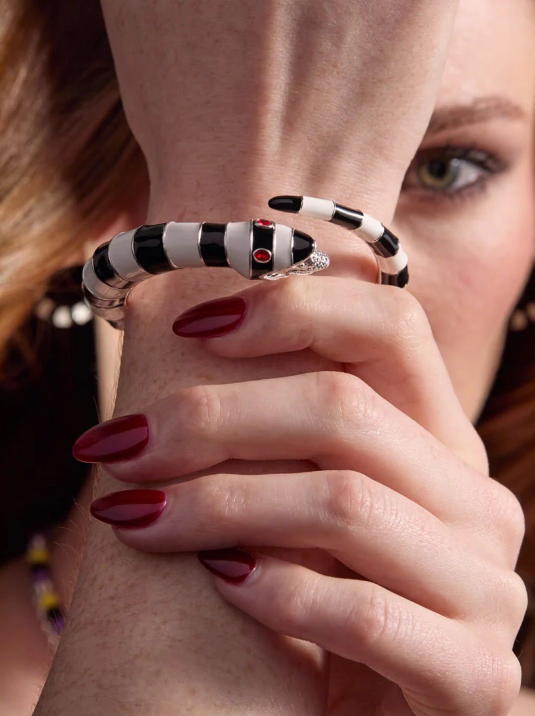 Close-up of a hand wearing a black and white patterned bracelet with red accents.