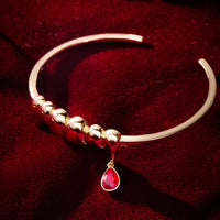 Gold bracelet with a red gemstone on a red background