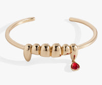 Gold bracelet with a red gemstone on a white background