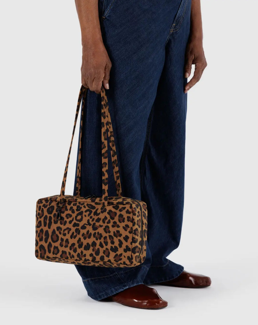 Person holding a leopard print handbag against a white background