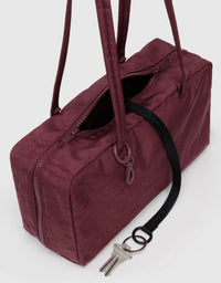 Maroon duffel bag with a black strap on a white background