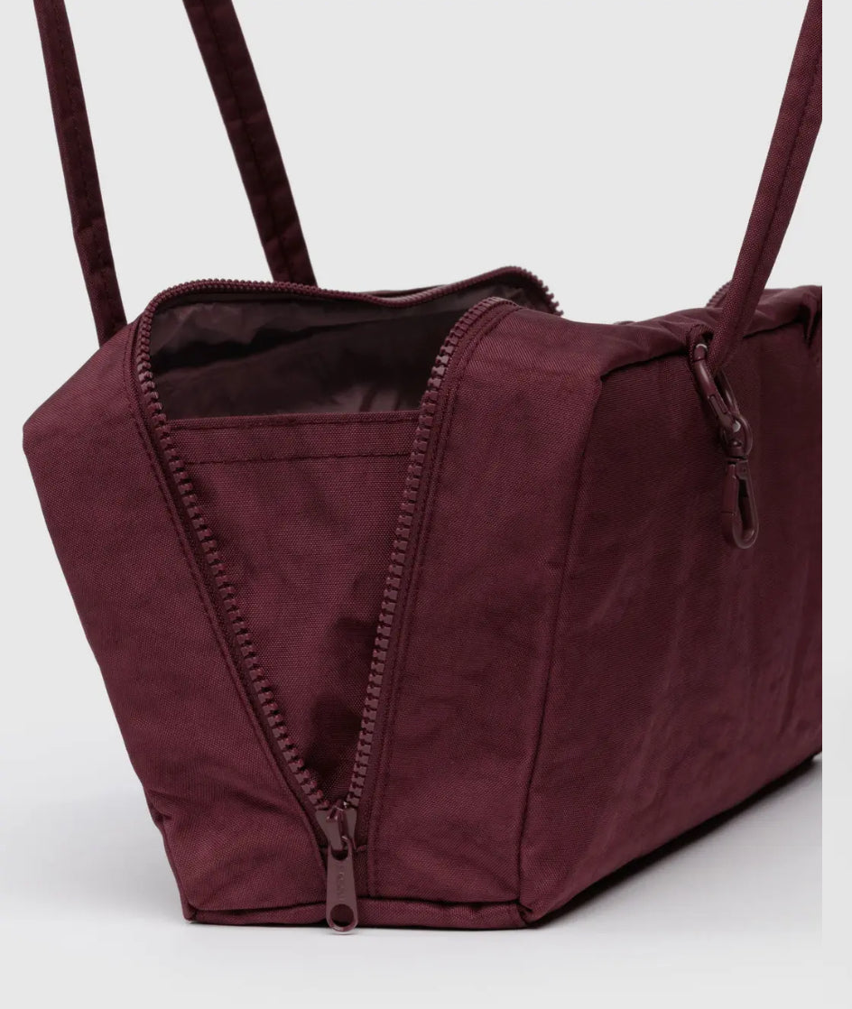 Maroon duffel bag with a zipper on a white background