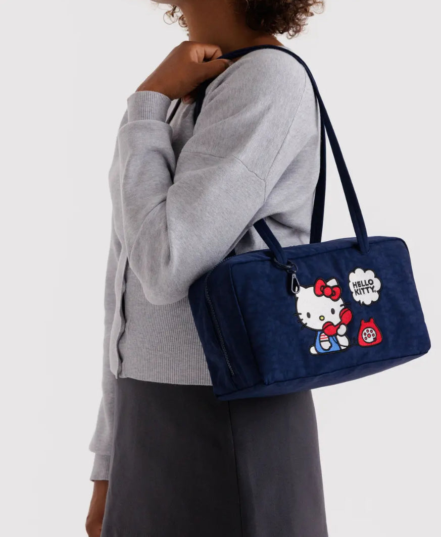 Person holding a blue bag with Hello Kitty design on a white background