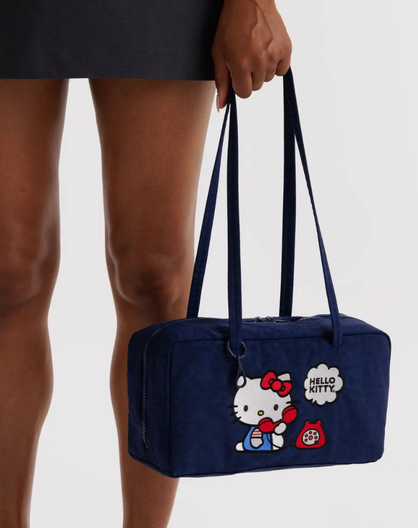 Navy blue bag with Hello Kitty design held by a person on a plain background