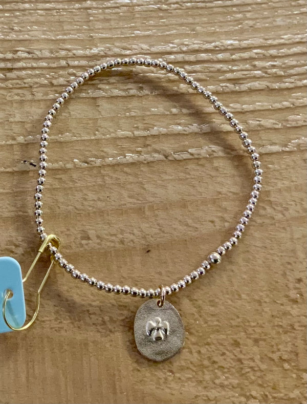 Silver beaded bracelet with a pendant on a wooden surface