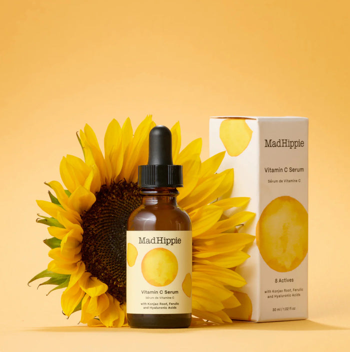 Mad Hippie Vitamin C Serum bottle, dropper, and packaging with a sunflower on a yellow background