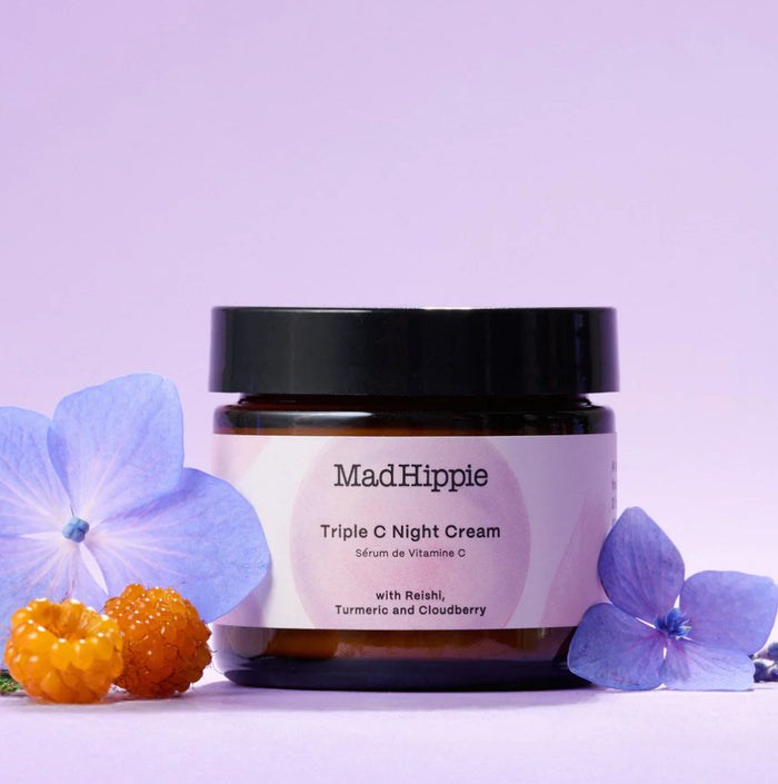Jar of Mad Hippie Triple C Night Cream with purple flowers and berries on a light purple background
