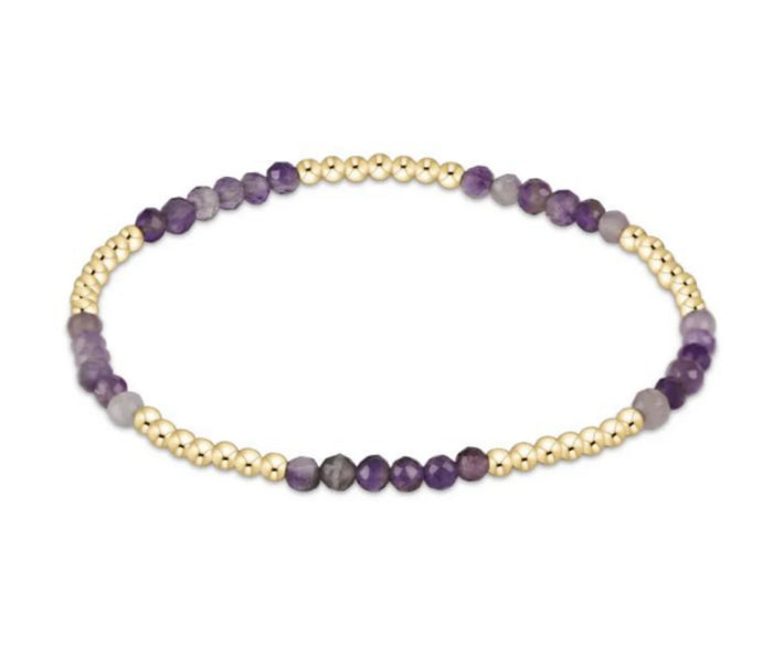 Bracelet with purple and gold beads on a white background