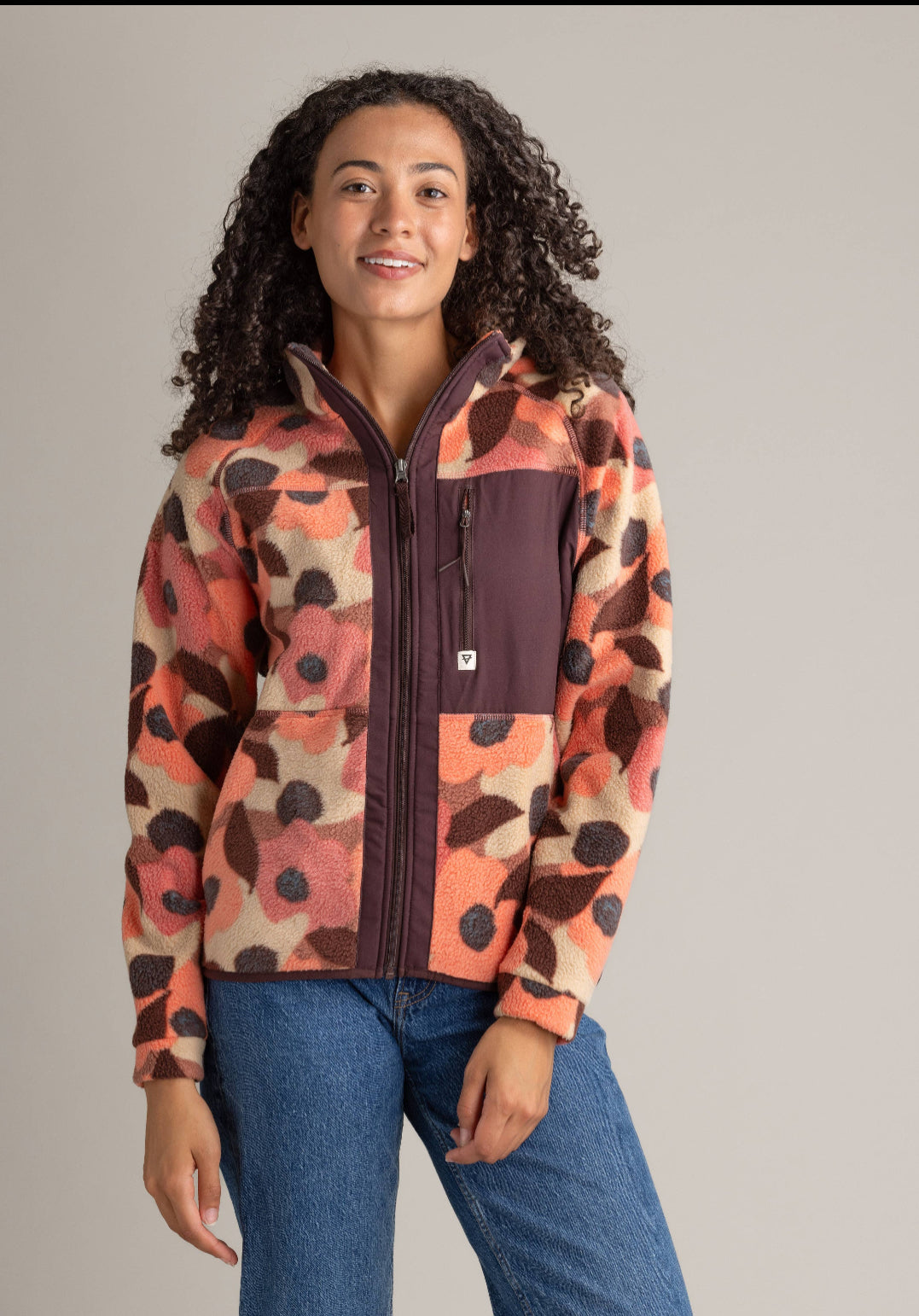 Woman wearing a colorful patterned jacket against a plain background