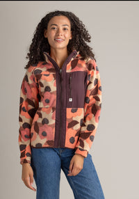 Woman wearing a colorful patterned jacket against a plain background