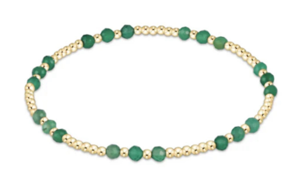Bracelet with green beads and gold accents on a white background