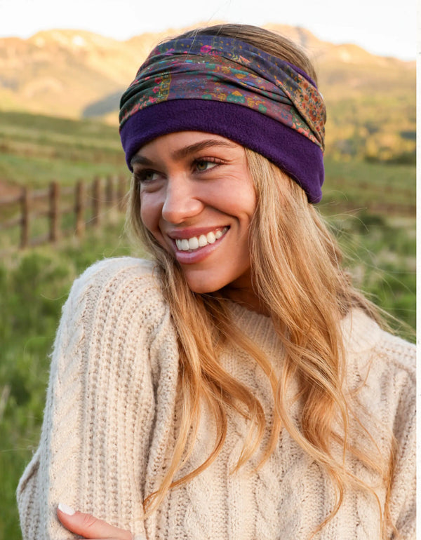 Woman wearing a colorful headscarf and purple beanie in a natural setting